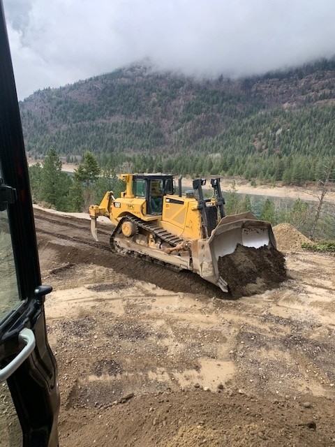Dozer on a riverside site with mountain backdrop